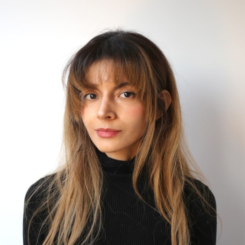 Mariana Oka, photographed against a plain wall in a black roll-neck.